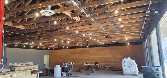 Commercial interior with exposed wood beams, string lights, ceiling fans and a cedar accent wall