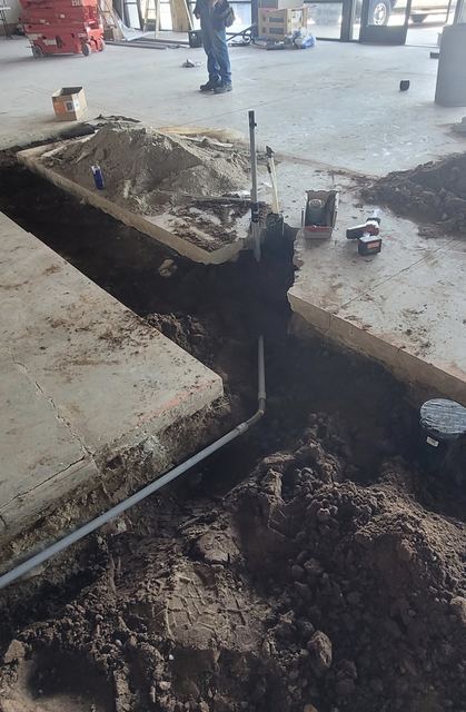 Trench cut through a concrete slab with PVC conduit laid in the ground